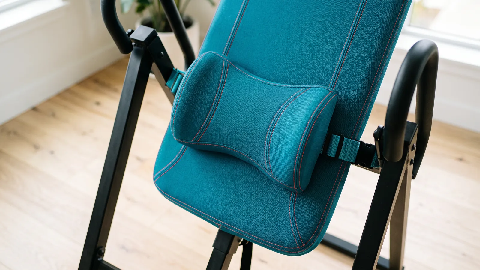Close-up of a teal lumbar pad strapped to an inversion table backrest
